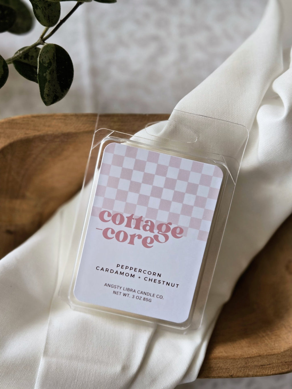 Wax melts labeled 'cottagecore' on a white fabric background with a plant.