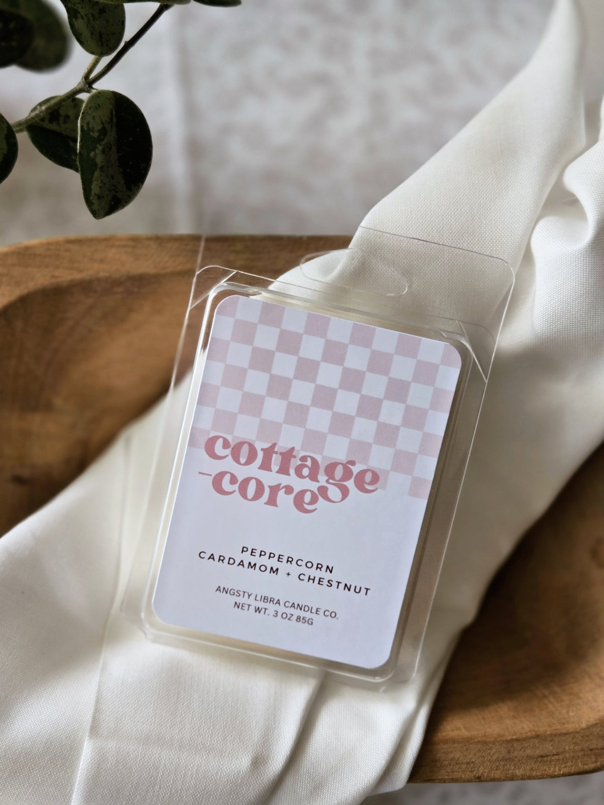 Wax melts labeled 'cottagecore' on a white fabric background with a plant.