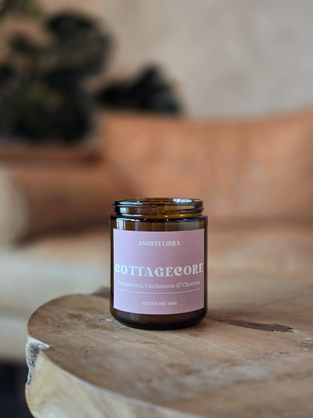 Candle jar labeled 'Cottagecore' on a wooden surface with a blurred background